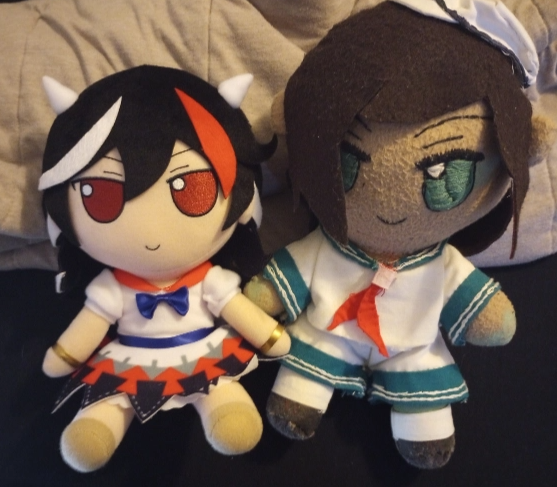 a photo of a homemade plushie of Captain Murasa from Touhou in the style of the Fumofumo line of plushies, next to an official Seija plushie from the line